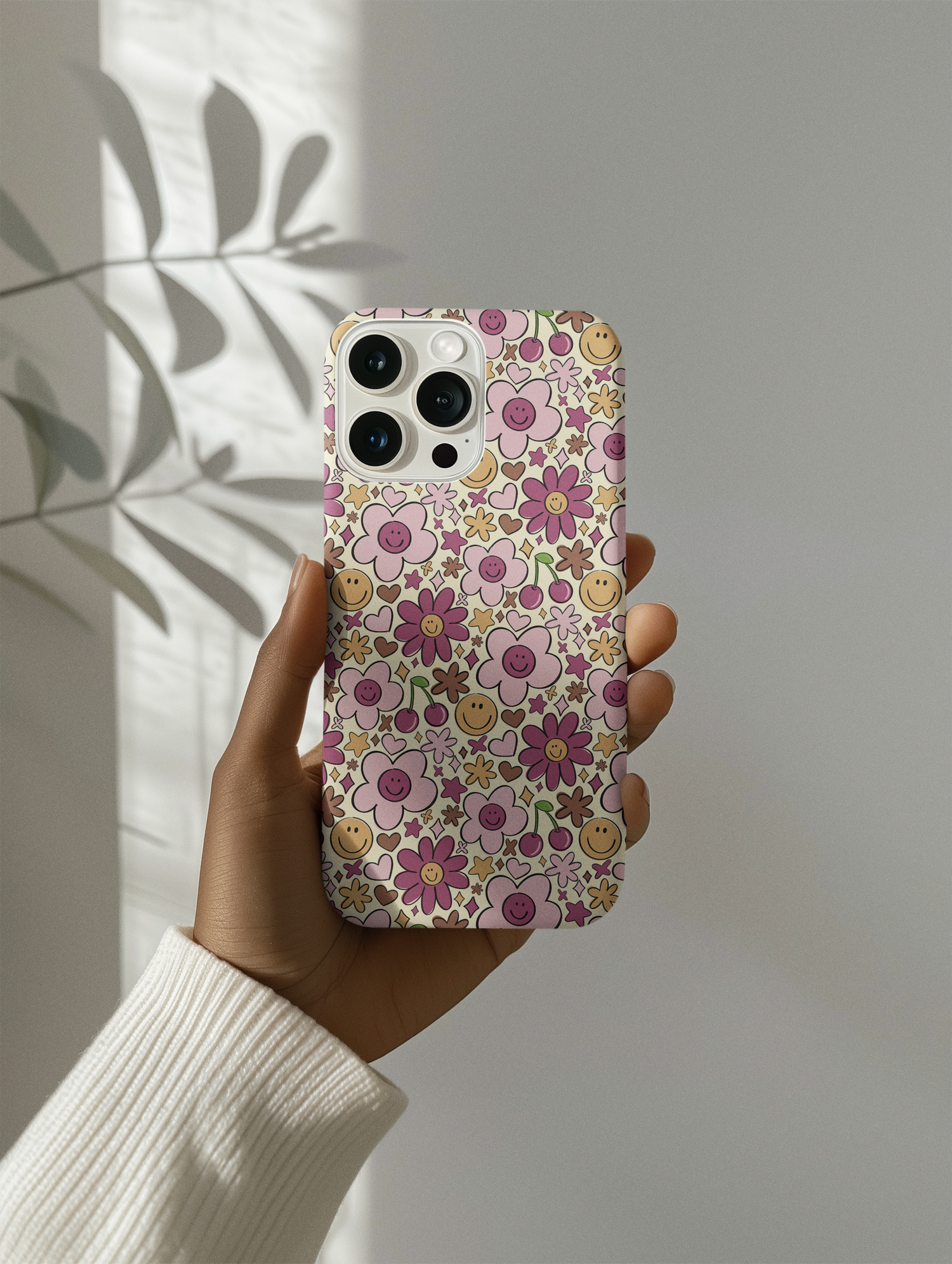 Retro Phone Case for iphone with groovy floral pattern being held up against a white wall with natural shadows